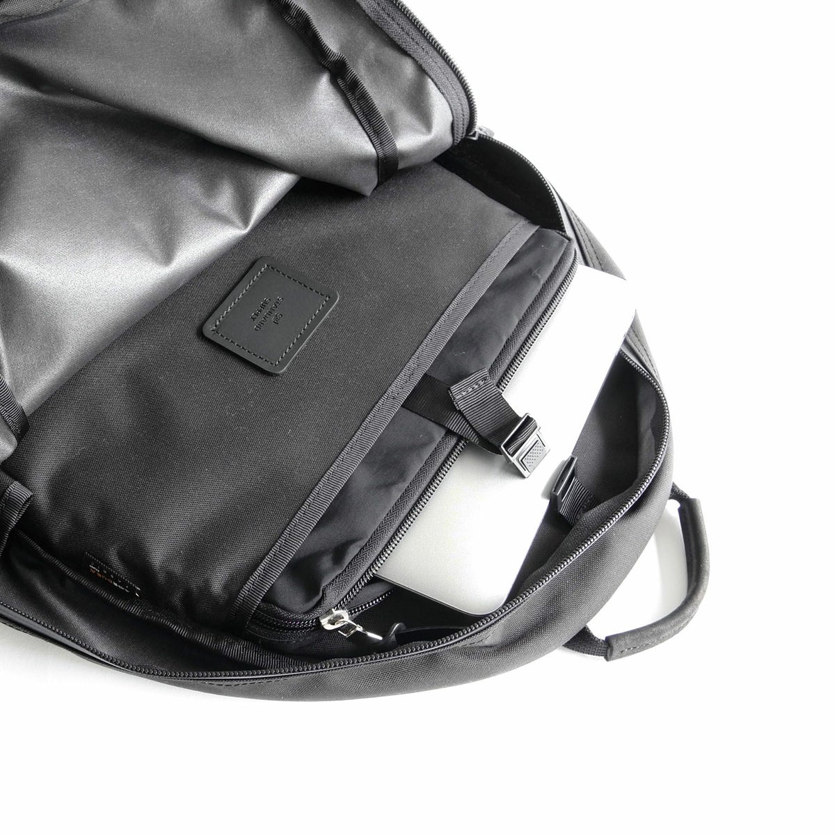 背面側には、プラスチックパーツで留められる</br>スリットポケットがありPCなどを収納できます。