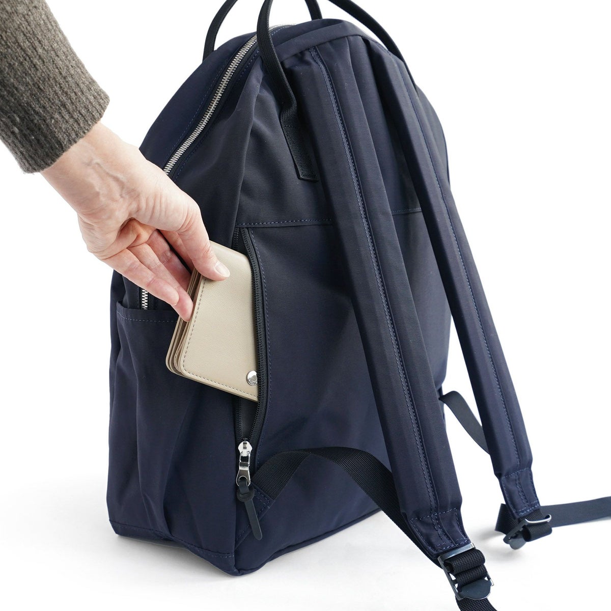 背面にはファスナーで開閉できるポケットが付いており、</br>背負った状態でも出し入れができます。